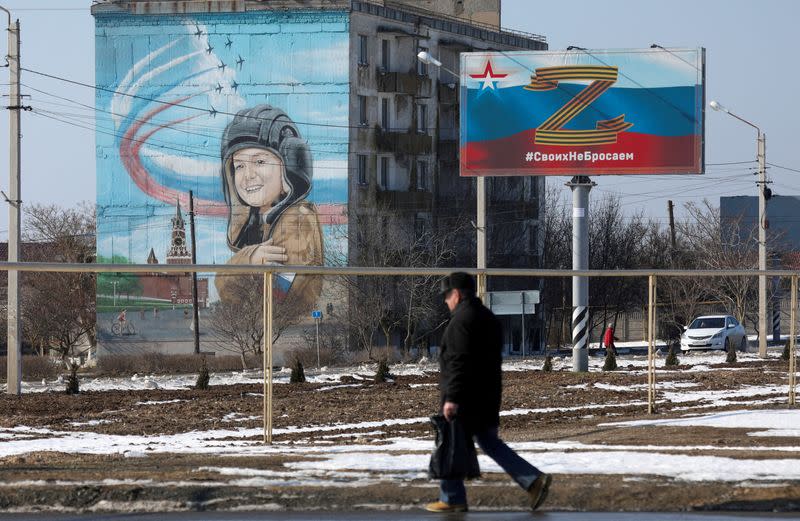 FILE PHOTO: A pedestrian walks past a billboard displaying the symbol "Z" in support of Russian armed forces in Ukraine, in the settlement of Chernomorskoye, Crimea