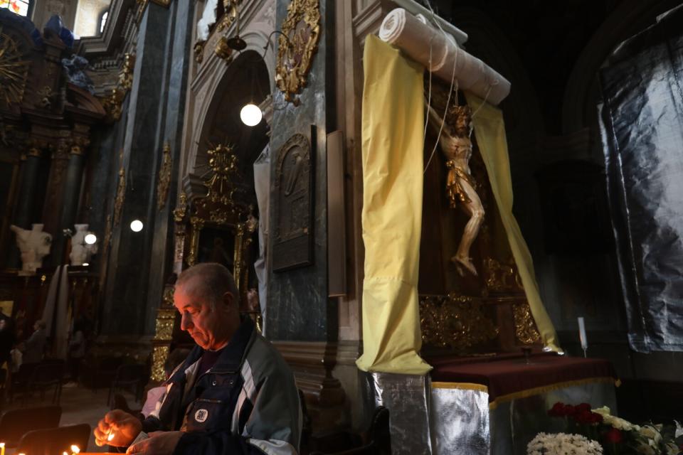 A wrap is lowered to cover the crucifix in the event of a bombing in Lviv, Ukraine.