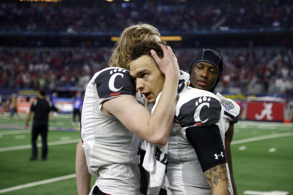 Cincinnati quarterback Desmond Ridder, center, is hugged by a teammate after the Cotton Bowl NCAA College Football Playoff semifinal game, Friday, Dec. 31, 2021, in Arlington, Texas. Alabama won 27-6. (AP Photo/Michael Ainsworth)