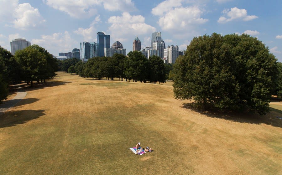 A man sunbathes amidst patches of dried-out lawn from a lack of rain in Atlanta, Thursday, Oct. 3, 2019. (AP Photo/David Goldman)