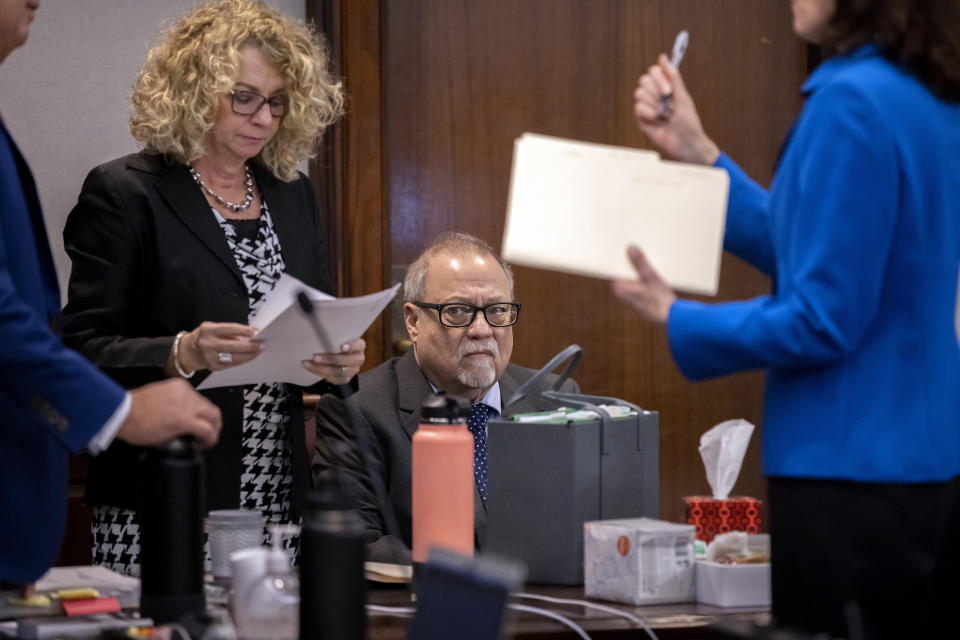 Greg McMichael, center, sits with his attorney Laura Hogue, left, before the start of his trial in the Glynn County Courthouse, Tuesday, Nov. 9, 2021, in Brunswick, Ga. Greg McMichael along with his son Travis and a neighbor, William "Roddie" Bryan are charged with the February 2020 slaying of 25-year-old Ahmaud Arbery. (AP Photo/Stephen B. Morton, Pool)