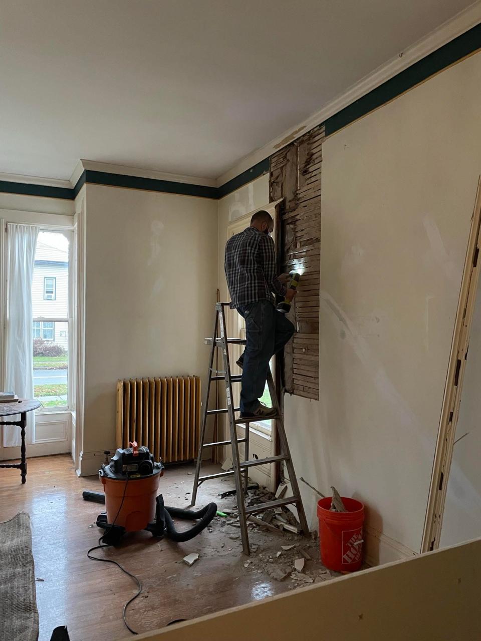 A man works on paneling inside a historic home.