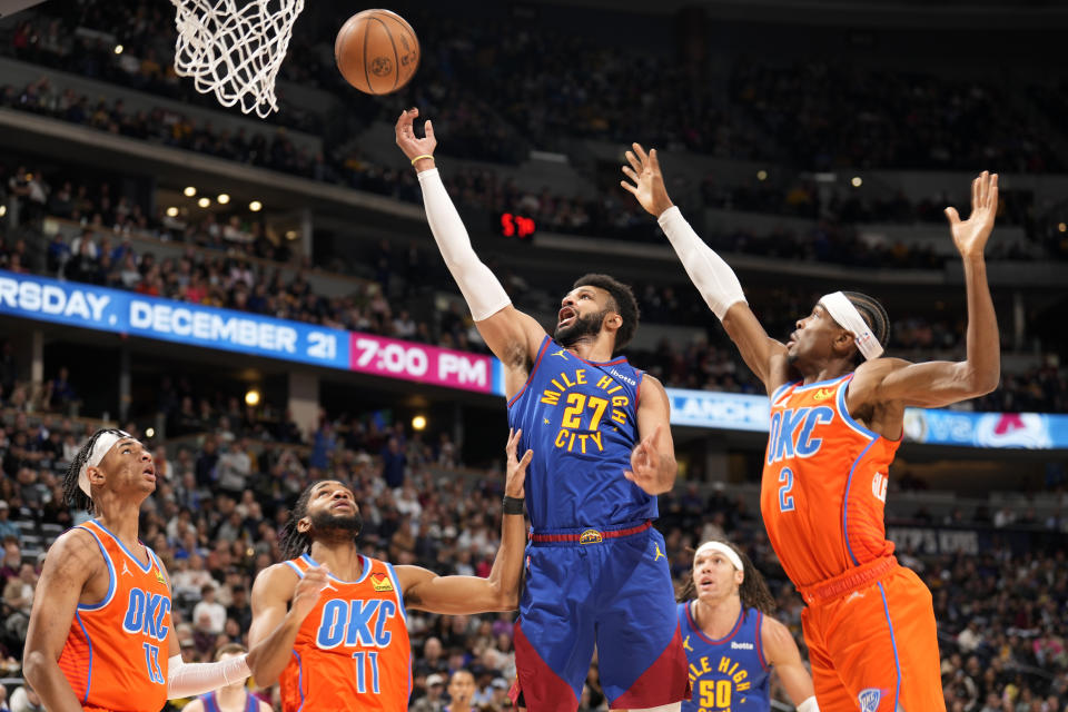 Denver Nuggets guard Jamal Murray (27) drives to the basket as Oklahoma City Thunder forward Ousmane Dieng (13), guard Isaiah Joe (11) and guard Shai Gilgeous-Alexander (2) defend in the first half of an NBA basketball game Saturday, Dec. 16, 2023, in Denver. (AP Photo/David Zalubowski)