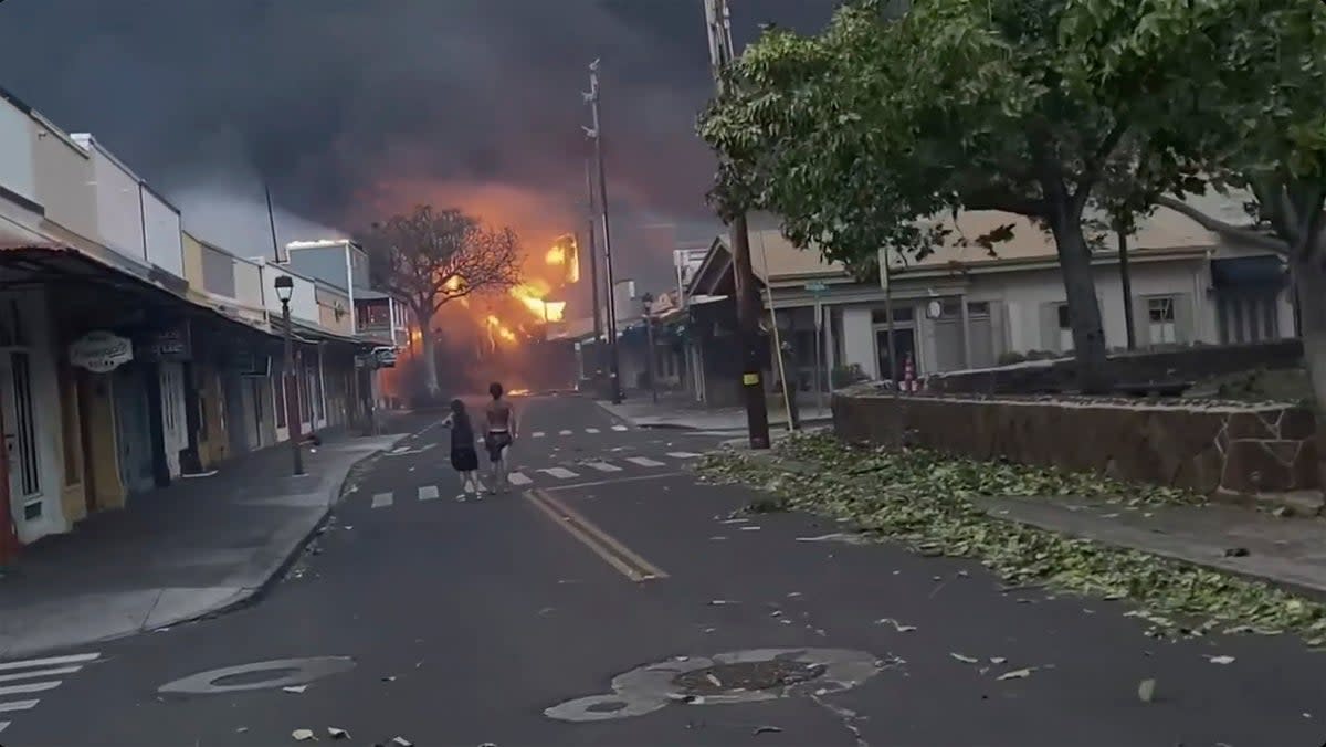 People watch as smoke and flames fill the air from raging wildfires on Front Street in downtown Lahaina, Maui on Tuesday, Aug. 9, 2023 (Alan Dickar via AP)