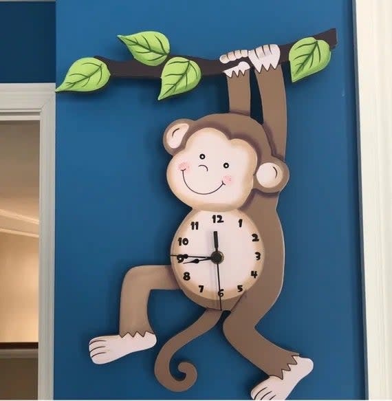 the monkey clock against a blue wall