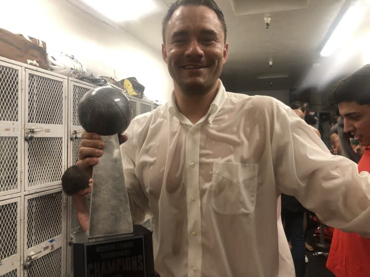 A soaked Harvard-Westlake coach David Rebibo holds the Mission League tournament championship trophy after his team's 81-66 win over Chaminade. "Open Division, baby," Rebibo told his team in the locker room.