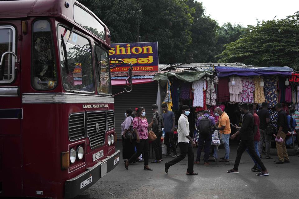 People arrive for their daily work in the central market area in Colombo, Sri Lanka, Tuesday, March 21, 2023. The International Monetary Fund said Monday that its executive board has approved a nearly $3 billion bailout program for Sri Lanka over four years to help salvage the country's bankrupt economy.(AP Photo/Eranga Jayawardena)