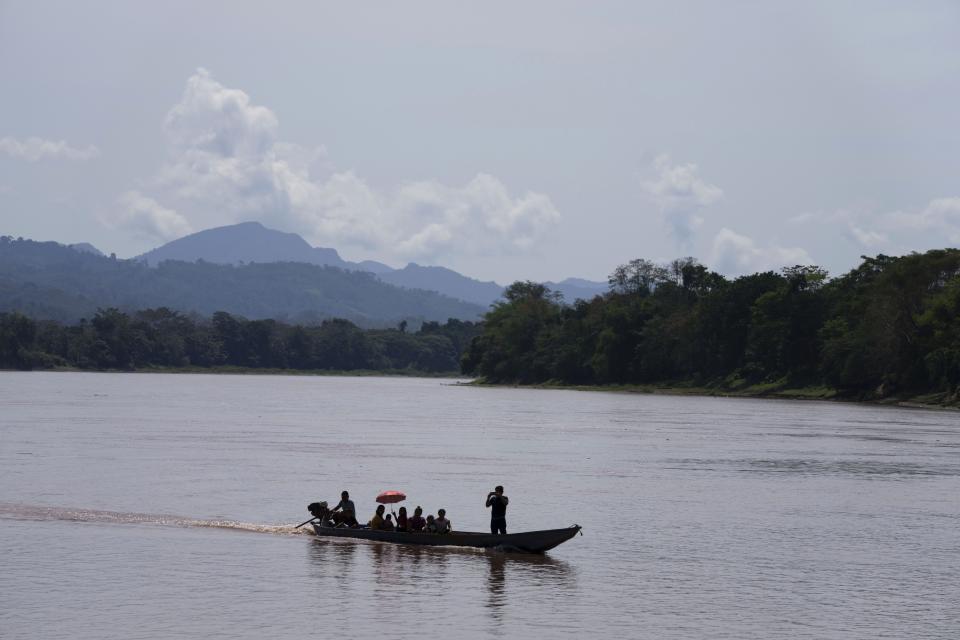 Residents travel down the Huallaga River in the Chazuta community within view of the Cordillera Azul National Park, in Peru's Amazon, Sunday, Oct. 2, 2022. Residents in Kichwa Indigenous villages in Peru say they fell into poverty after the government turned their ancestral forest into a national park, restricted hunting and sold forest carbon credits to oil companies. (AP Photo/Martin Mejia)