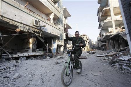 A Shi'ite fighter rides his bicycle on a damaged street after soldiers loyal to Syria's President Bashar al-Assad took control of Hujaira town from rebel fighters, in the town south of Damascus November 21, 2013. REUTERS/Alaa Al-Marjani