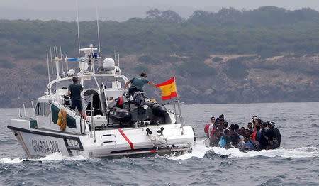 Spanish Civil Guards try to stop migrants before disembarking from a dinghy at Del Canuelo beach after they crossed the Strait of Gibraltar sailing from the coast of Morocco, in Tarifa, southern Spain, July 27, 2018. REUTERS/Stringer