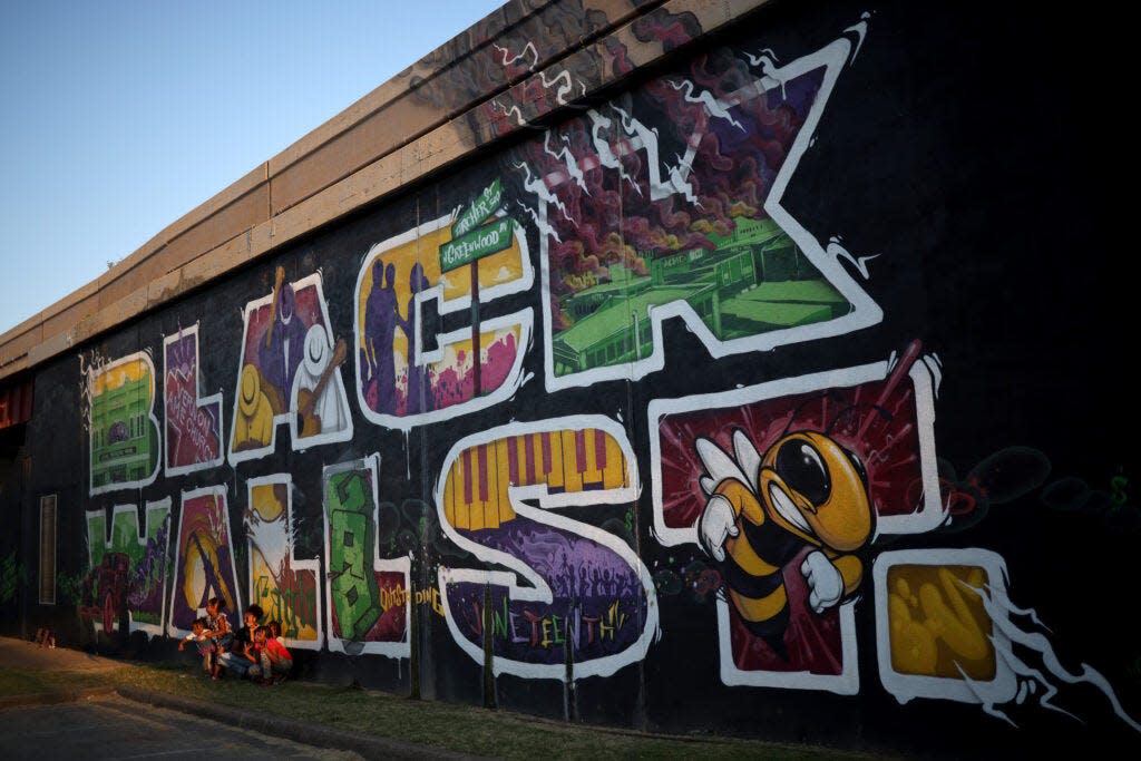 Children pose for a photo in 2020 in front of a mural marking Black Wall Street, also called the Greenwood District in Tulsa.