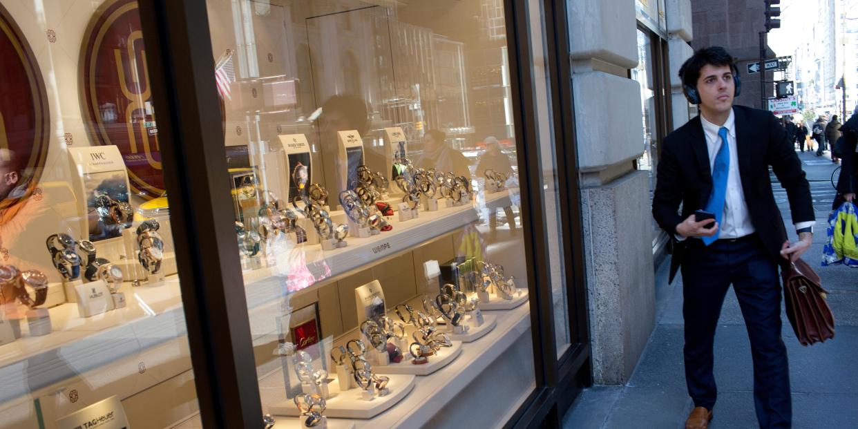 A young man in a suit walks past a luxury watch shop on 5th Avenue in midtown Manhattan.