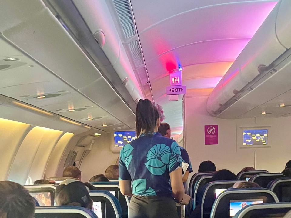 A flight attendant onboard Hawaiian with a flower-themed uniform.