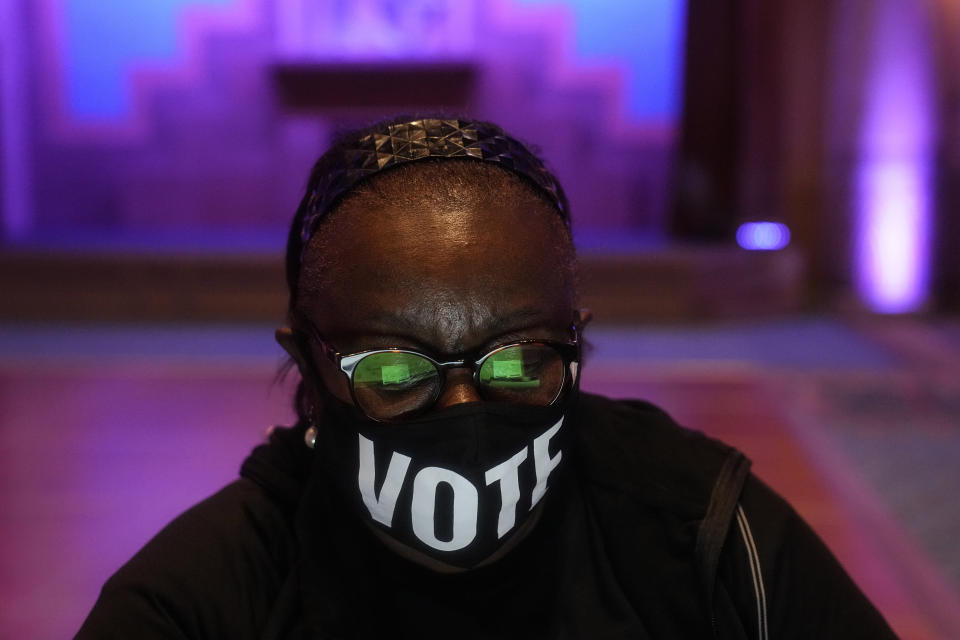 A poll worker wears a "vote" mask as they check in voters on Election Day, Tuesday, Nov. 8, 2022, in Atlanta. (AP Photo/Brynn Anderson)