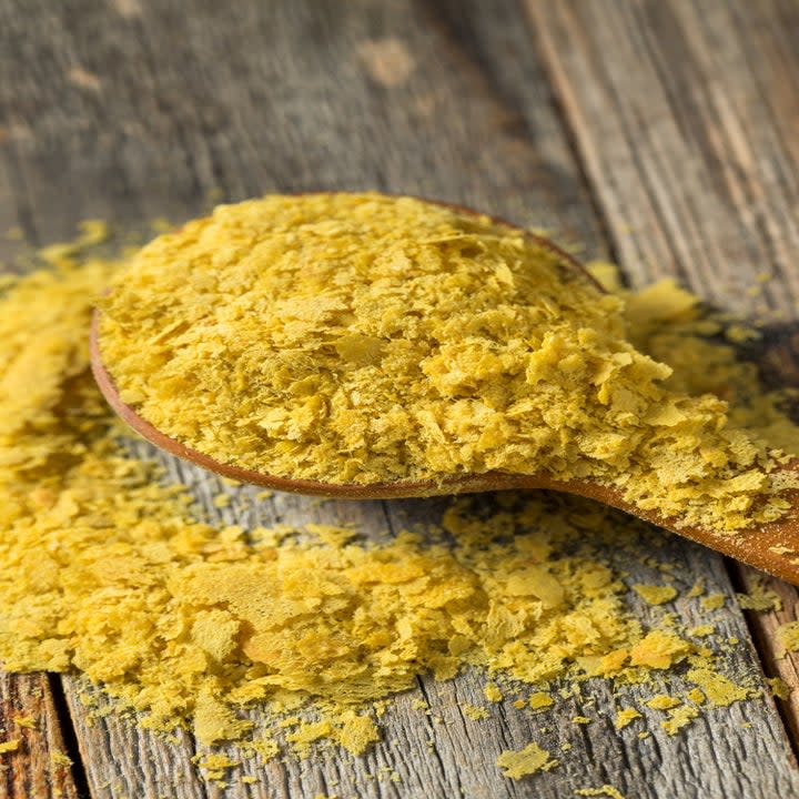 Nutritional yeast flakes poured over a wooden spoon