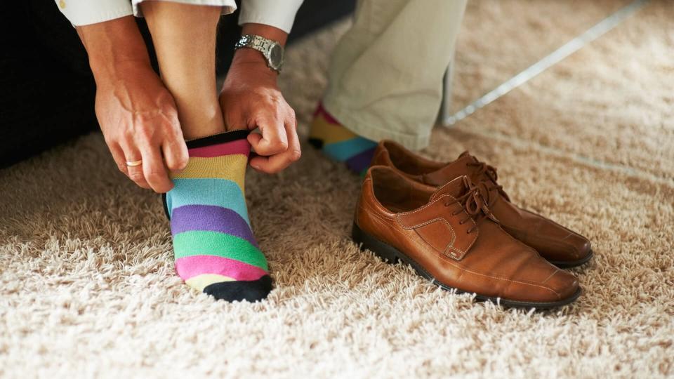 Man putting on colorful socks.