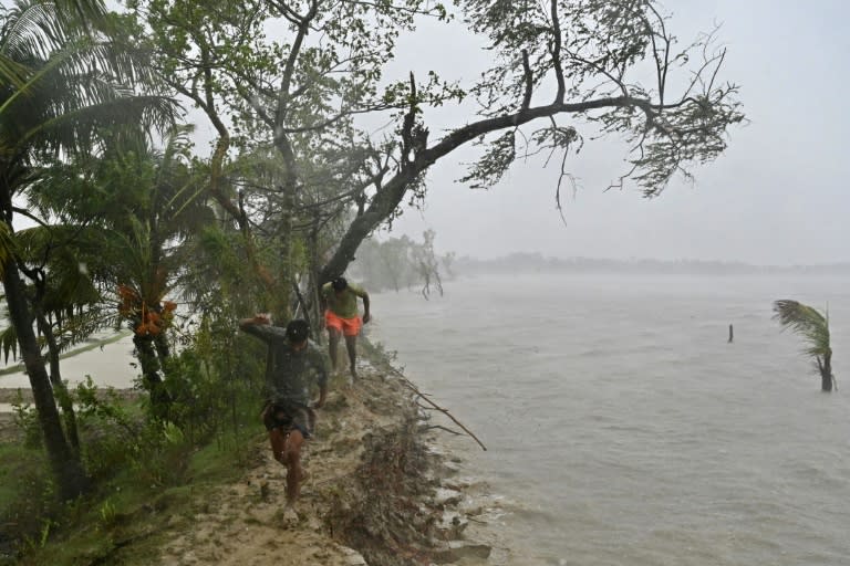 People walk on a damaged embankment during heavy rains in Patuakhali in May 2024, after Cyclone Remal made landfall (Munir Uz Zaman)