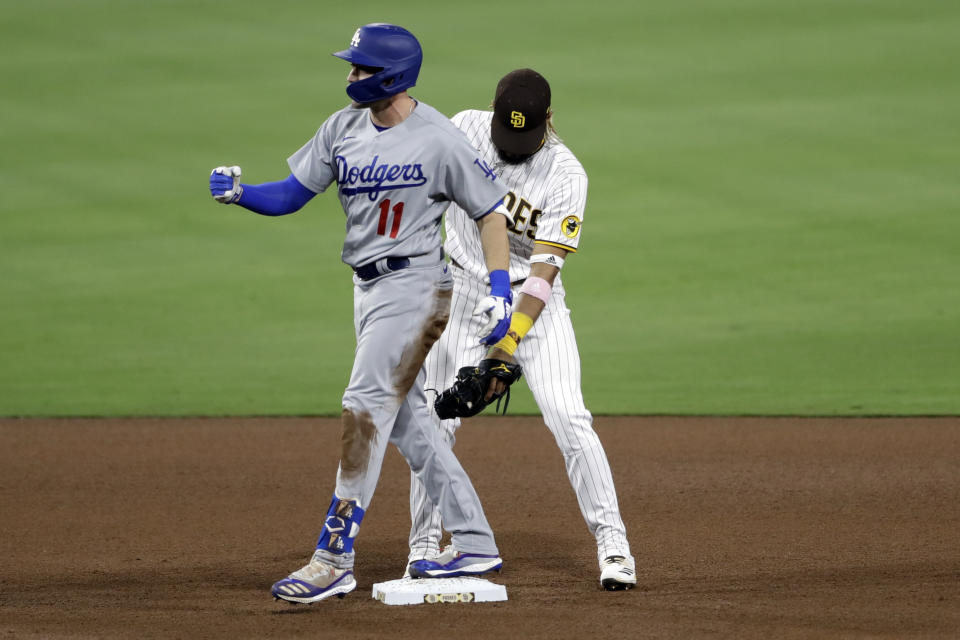 Los Angeles Dodgers' AJ Pollock, left, reacts after hitting an RBI double, next to San Diego Padres shortstop Fernando Tatis Jr. during the seventh inning of a baseball game Tuesday, Aug. 4, 2020, in San Diego. (AP Photo/Gregory Bull)