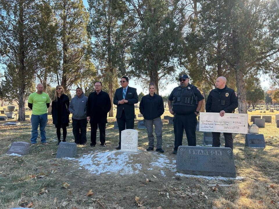 Pueblo police present Roselawn Cemetery staff a ceremonial check for the restoration of Elmer Trout's headstone