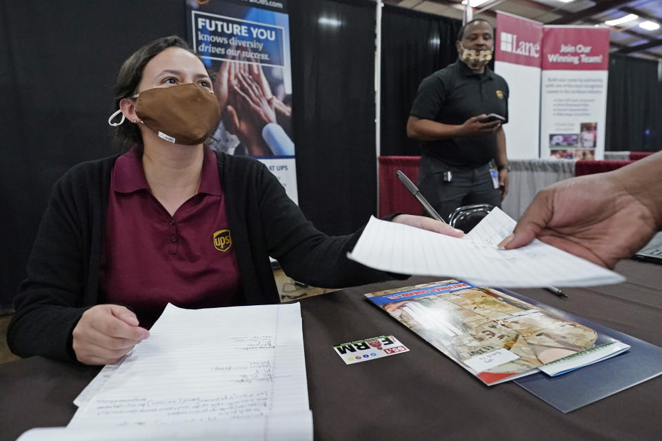 Ariel Jones, a United Parcel Service human resources intern, hands an applicant an information sheet, while the human resources specialist for the company, Mareno Moore, right, monitors the interaction during the Lee County Area Job Fair in Tupelo, Miss., Tuesday, Oct. 12, 2021. Employers representing a variety of manufacturing, production, service industry, medical and clerical companies attended the day long affair with an eye towards recruitment, hiring, training and retention. (AP Photo/Rogelio V. Solis)