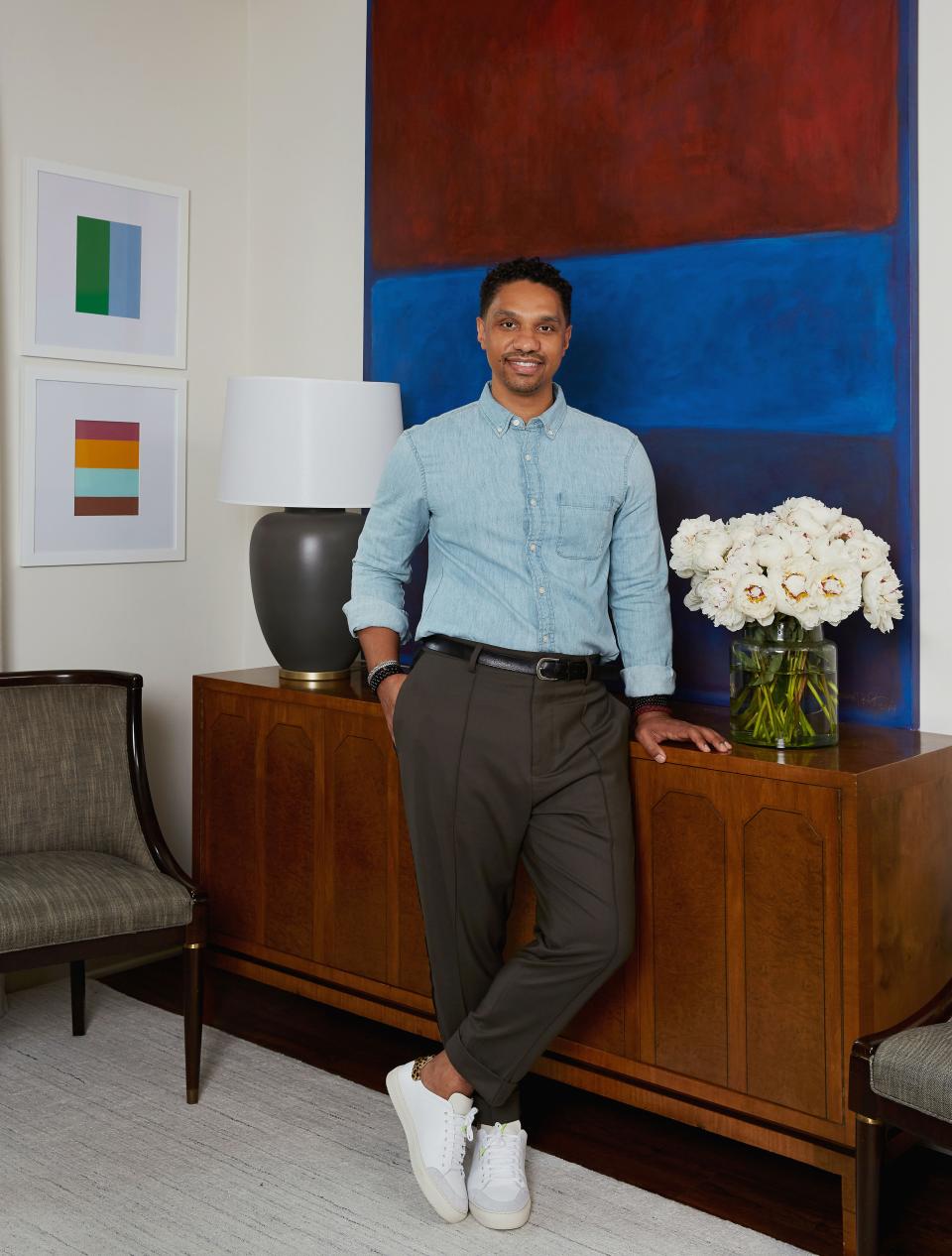 Risdon poses in his living room next to a console table he purchased at Kamelot Auctions in Philadelphia. The large canvas work beside him is by Jaime Karf; the smaller framed acrylics behind him are by William Radawec. Fox Mill Lighting & Supply Co. produced the table lamp.