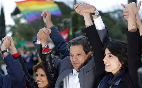 Workers' Party presidential candidate Fernando Haddad, centre, and his running-mate Manuela d'Avila, right, hold a campaign rally - Credit: Eraldo Peres/AP