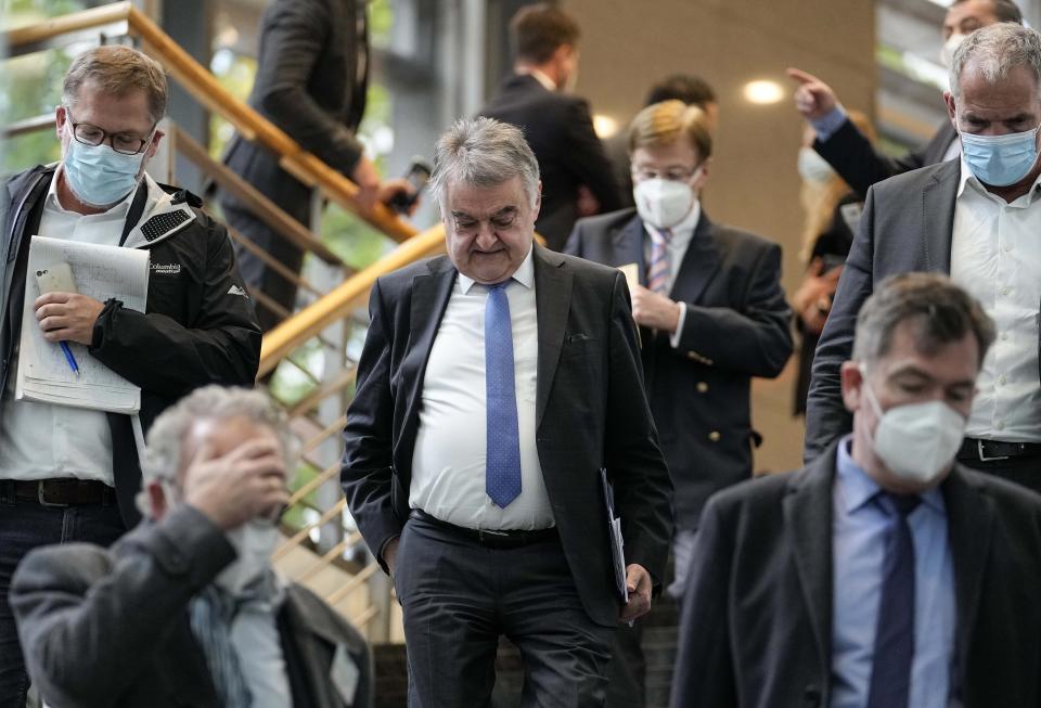 North Rhine-Westphalia's Interior Minister Herbert Reul, center, leaves after a press conference in Duesseldorf, Germany, after raids in severals German cities, Wednesday, Oct. 6, 2021. German police have carried out large-scale raids in 25 cities in connection with a suspected money-laundering network alleged to have funneled more than $162 million in ill-gotten gains abroad. (AP Photo/Martin Meissner)