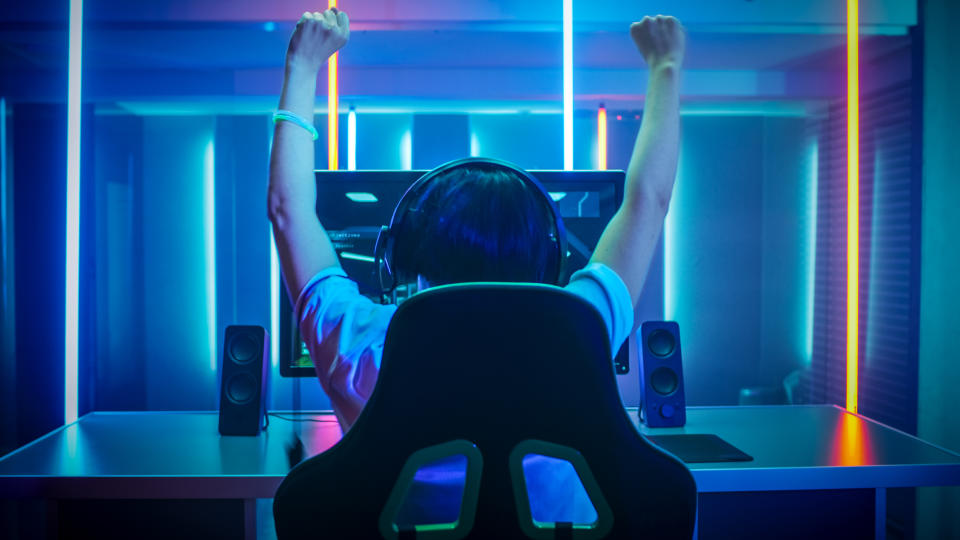 A person sitting at a computer raising their hands.