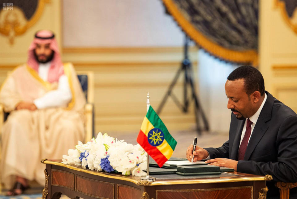 FILE - In this Sunday, Sept. 16, 2018 file photo released by the state-run Saudi Press Agency, Ethiopia's Prime Minister Abiy Ahmed, right, signs a peace accord with Eritrea as Saudi Crown Prince Mohammed bin Salman looks on in the distance in Jiddah, Saudi Arabia. Whether pressured to speak up after receiving assistance or making a diplomatic play for more, some African countries are expressing support for Saudi Arabia as shocking details in the killing of Jamal Khashoggi approached a crescendo, with South Sudan issuing a rare statement praising the Saudi position to defuse the crisis as "honorable". (Saudi Press Agency via AP, File)