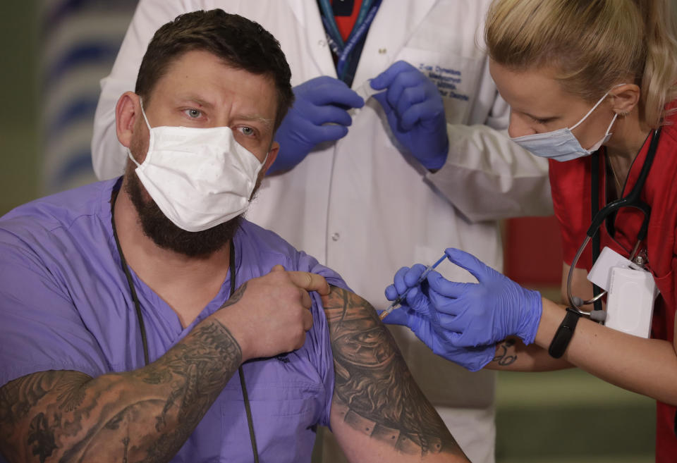 Slawomir Butkiewicz, left, the paramedic of the Interior Ministry hospital in Warsaw, the capital's main COVID-19 hospital, is getting the coronavirus vaccination in Warsaw, Poland, Sunday Dec. 27, 2020. (AP Photo/Czarek Sokolowski)