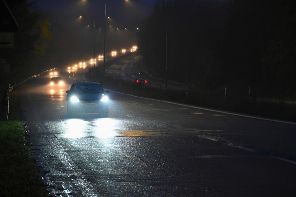 Cars driving down the road in the dark with their lights on