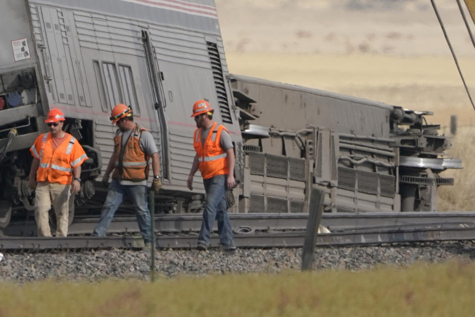 Workers walk Sunday, Sept. 26, 2021, next to cars from an Amtrak train that derailed Saturday just west of Joplin, Mont. The westbound Empire Builder was en route to Seattle from Chicago, with two locomotives and 10 cars. (AP Photo/Ted S. Warren)