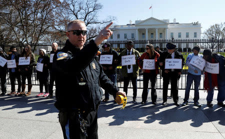 A policeman stands in front of protesters demonstrating against U.S. President Donald Trump and his plans to end Obamacare outside the White House in Washington, U.S., March 23, 2017. REUTERS/Kevin Lamarque