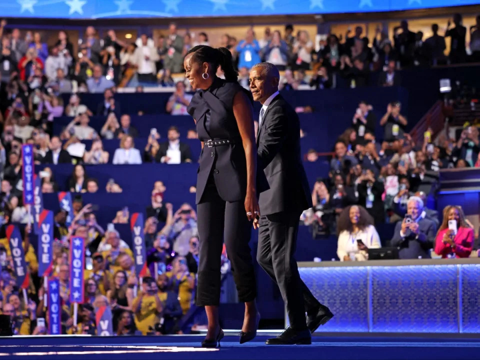 Former First Lady Michelle Obama greets her husband former President Barack Obama on the DNC stage on 20 August in Chicago (AFP via Getty Images)