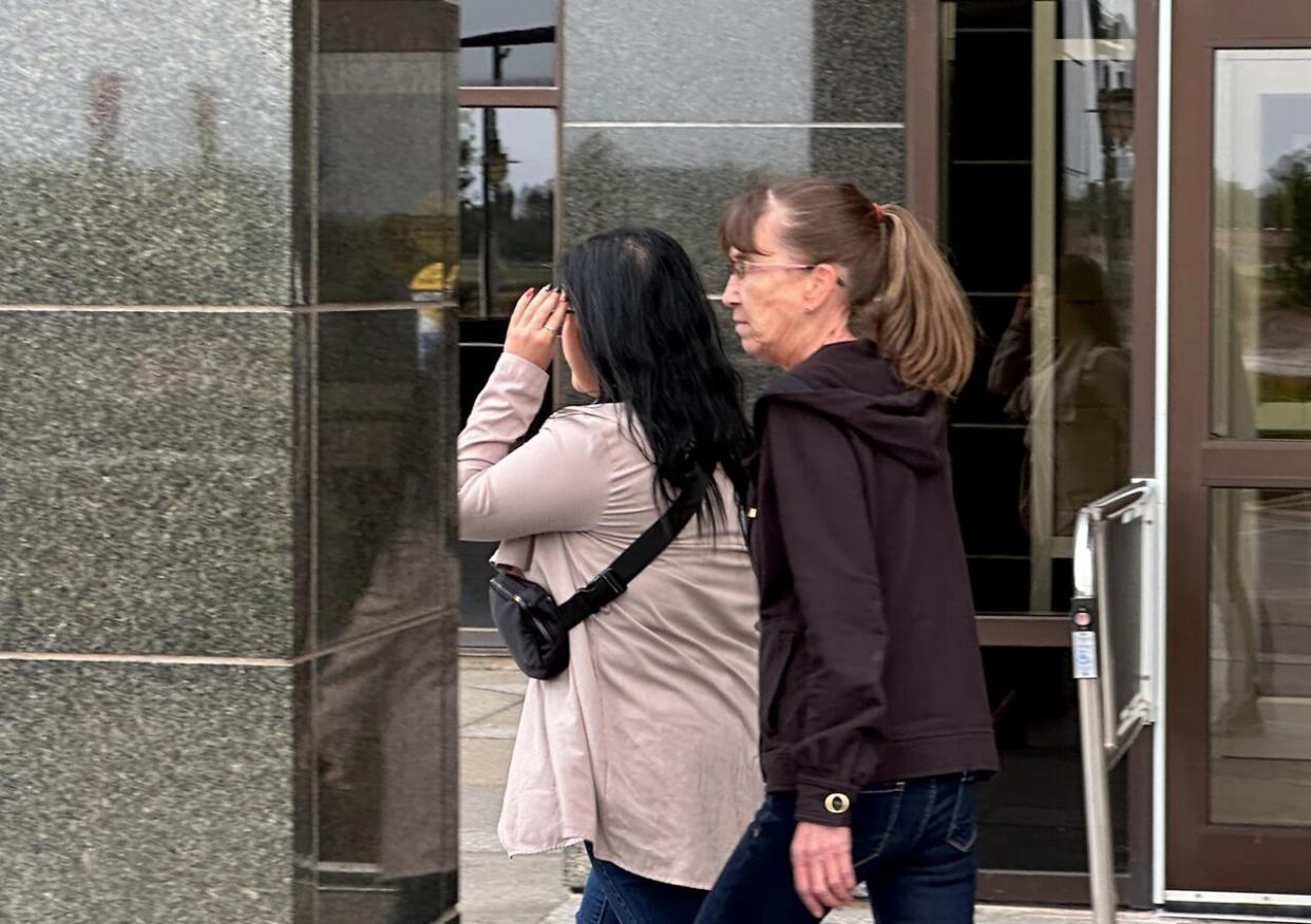 Bianca Chouinard, left, hides her face from reporters as she leaves the Moncton courthouse with a supporter after a sentencing hearing in September.  (Shane Magee/CBC - image credit)