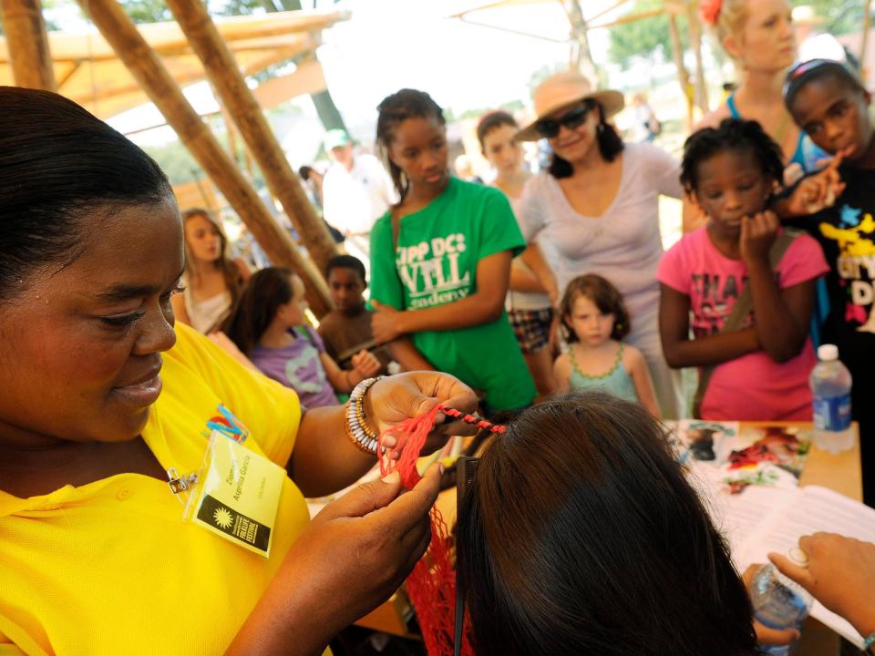 Ziomara Asprilla Garcia of Colombia braids brightly colored stands into a woman’s hair as others look on in 2011.