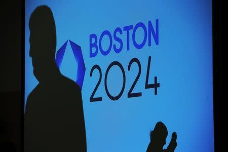 People cast shadows on a video display before a news conference explaining Boston's bid to host the 2024 Summer Olympics in Boston, Massachusetts January 21, 2015. REUTERS/Brian Snyder