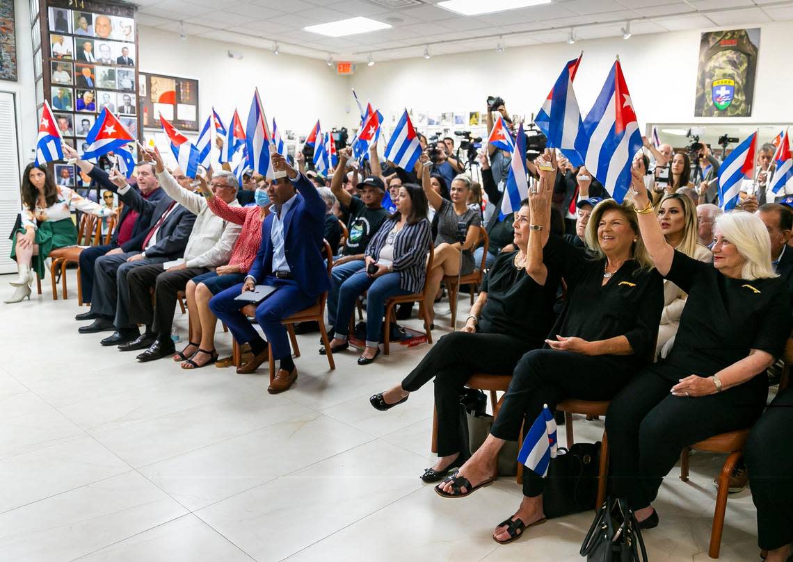 People raise their Cuban flags as they react during a press conference at the Brigade 2506 Bay of Pigs Museum and Library on Monday, July 11, 2022, in Miami, Fla. The press conference was held on the one-year anniversary of the July 11 protests, which saw the largest anti-government demonstrations in Cuba in several decades.