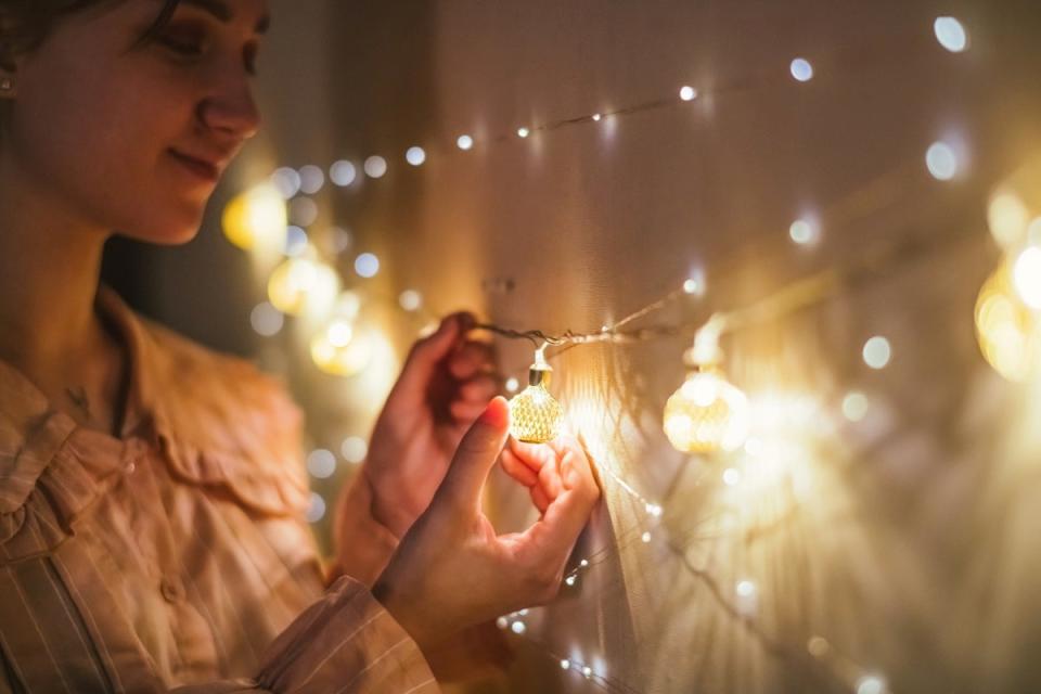 Woman replacing a Christmas light bulb on a string of clear lights.