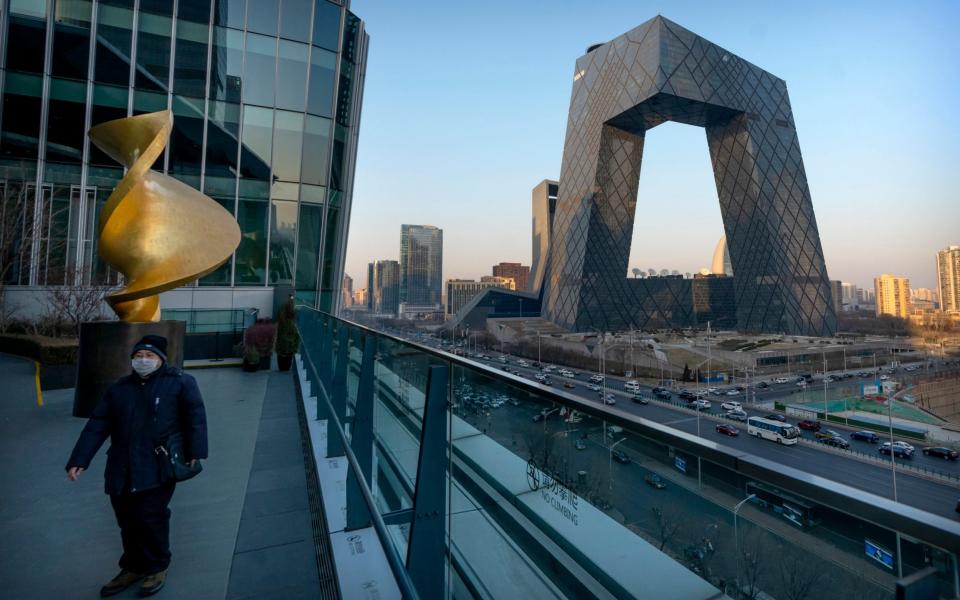 A man walks along an observation deck near the Beijing headquarters of CCTV, the state-owned broadcaster that owns CGTN, earlier in February - Mark Schiefelbein/AP