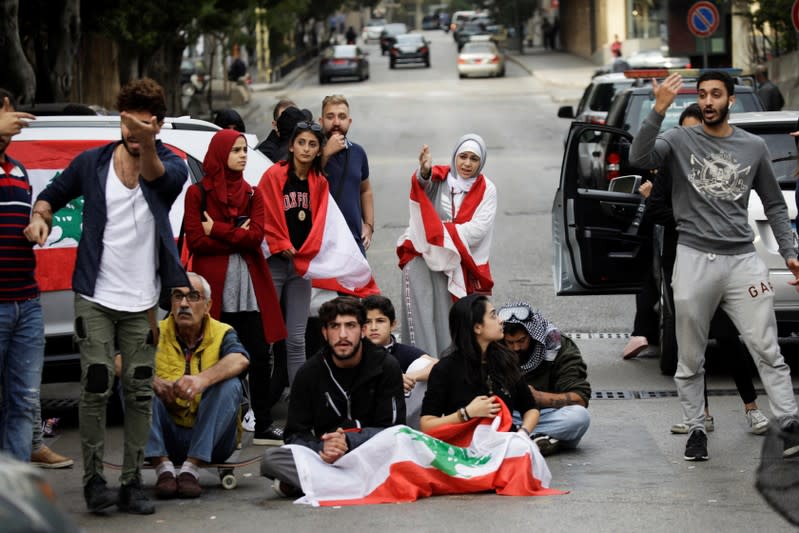 Protesters gesture towards a driver at a roadblock during ongoing anti-government demonstrations in Beirut