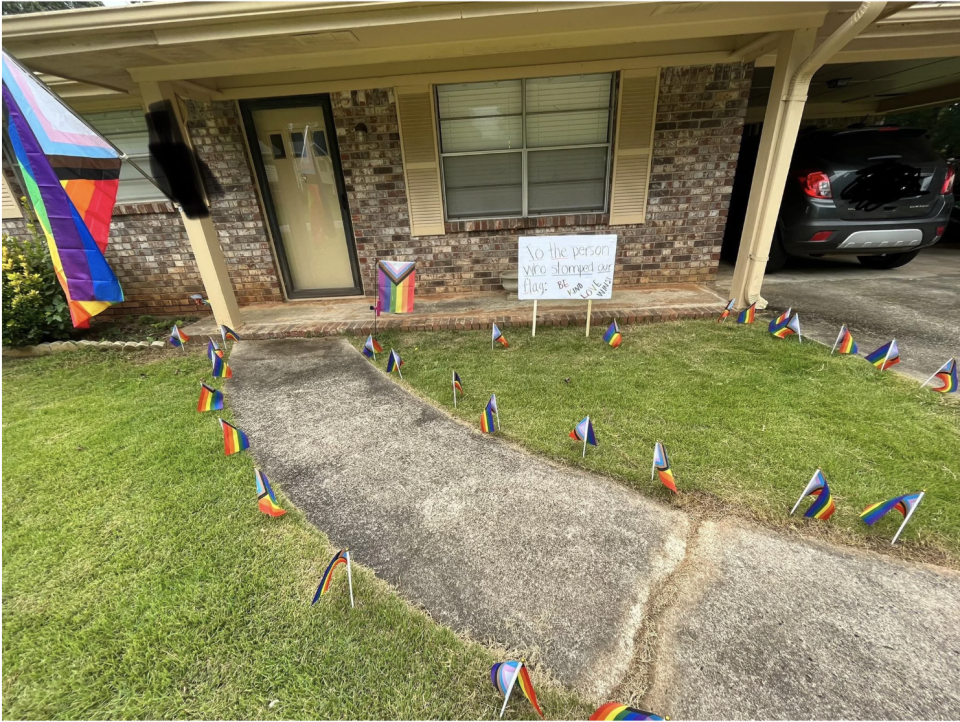 Front yard showing a pathway with Pride flags all along it and all around the grass and more on the porch