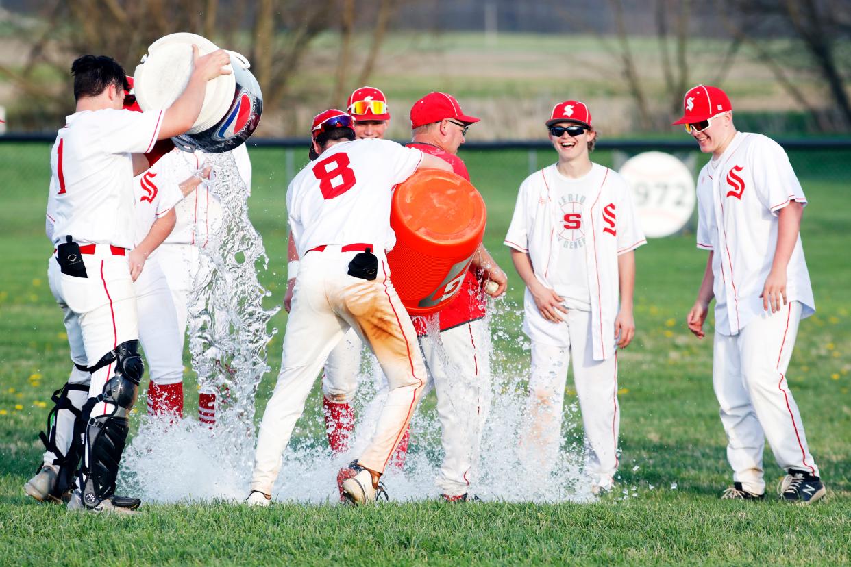 Sheridan seniors Caden Sheridan, left, and A.J. Winders dump buckets of ice water on head coach Doug Fisher after a 9-1 win against visiting Philo on Tuesday. The win was Fisher's 400th as a baseball coach.