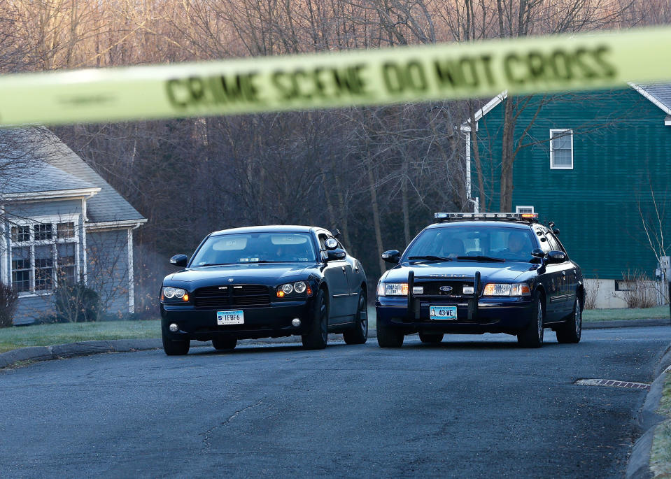 Police officers in Newtown, Connecticut, watch over a blocked-off section of the street where the Sandy Hook school shooter killed his mother at her home before opening fire at the nearby school, killing 26, in December 2012. / Credit: Jared Wickerham / Getty Images