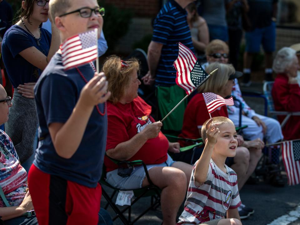 Children wave American flags at passing groups in the Jeffersonville, Indiana Freedom Parade. July 3, 2021