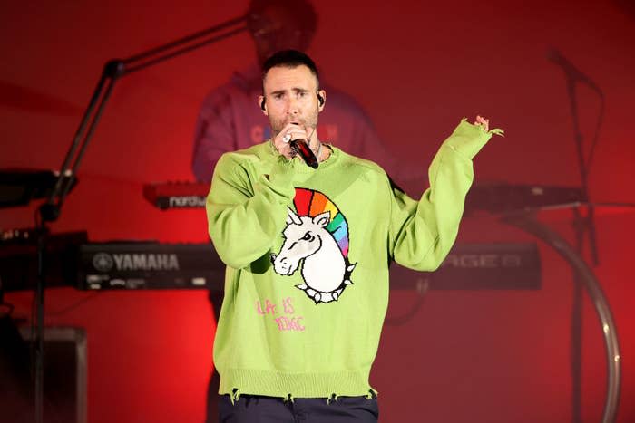 Adam performing at the Hollywood bowl, he wears a lime green sweater with a unicorn painted on it and the words "LA is toxic" in all caps