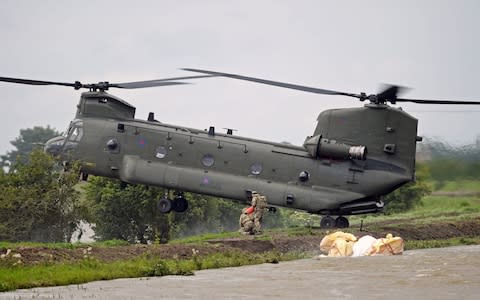 An RAF Chinook helicopter lands on the edge of the River Steeping  - Credit: PA
