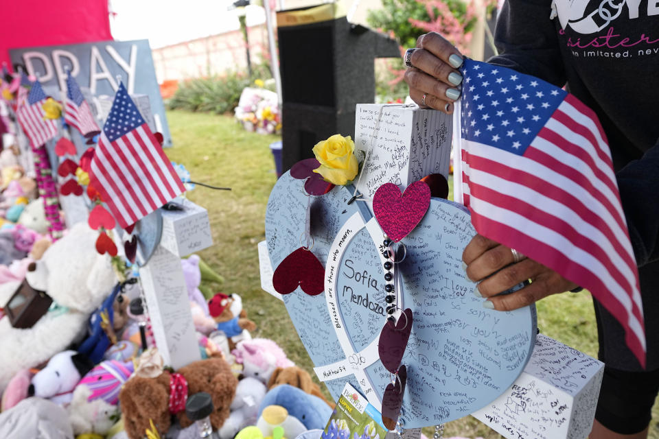 Inga VanWagoner, of Allen, Texas, who served in the U.S. Army, places flags atop crosses at a makeshift memorial by the mall where several people were killed, Wednesday, May 10, 2023, in Allen, Texas. / Credit: Tony Gutierrez / AP