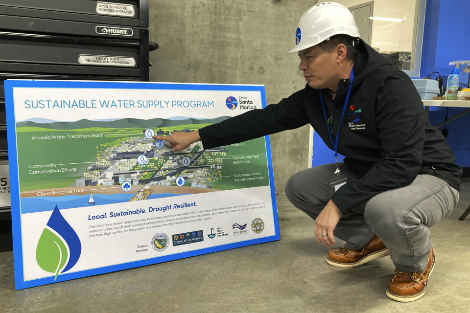 Sunny Wang, water resources manager for Santa Monica, points to a poster that shows the city's water infrastructure Tuesday, Jan. 17, 2023, in Santa Monica, Calif. In Santa Monica, the new water project captured nearly 2 million gallons (7,600 cubic meters) of runoff that once treated gets used for plumbing, irrigation or pumped back into the city’s aquifer. Wang said the project will eventually save an average of about 40 million gallons (151,000 cubic meters) per year. (AP Photo/Brian Melley)