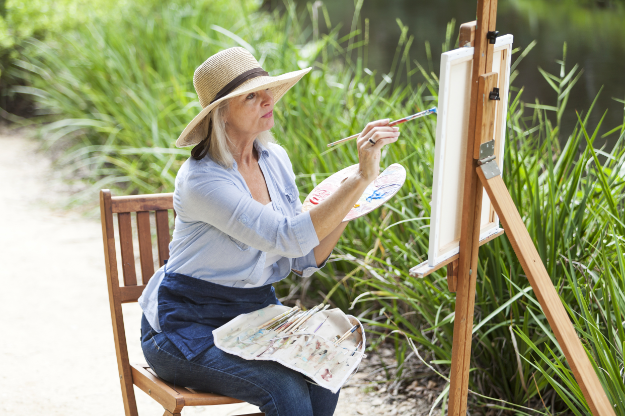 Older woman painting outside